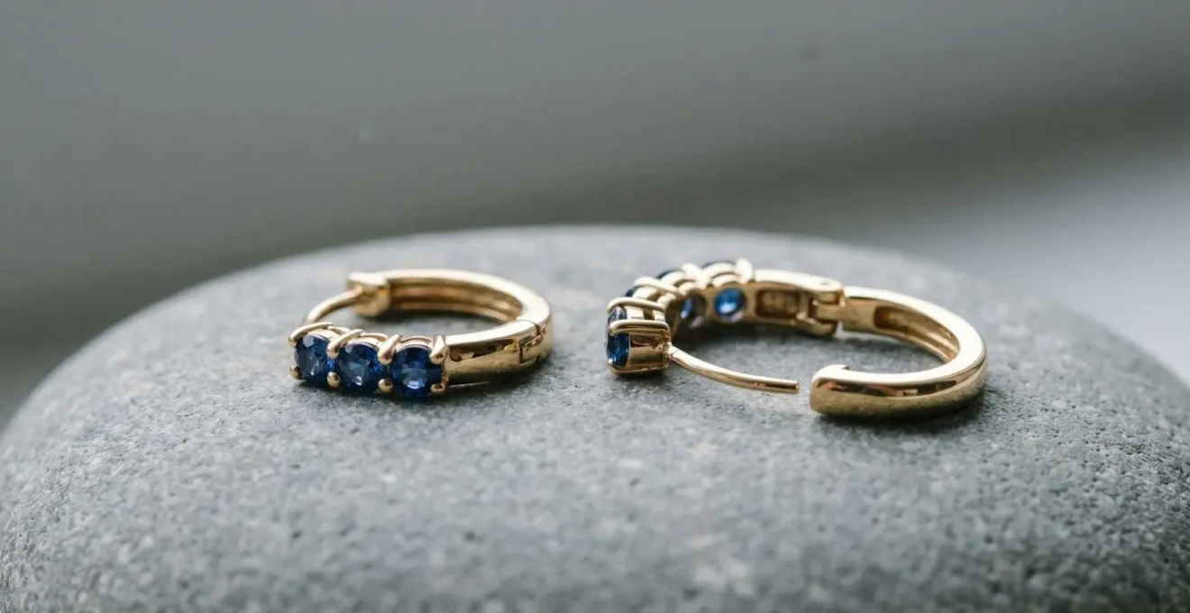 Gros plan sur une boucle d'oreille dormeuse en or avec saphir bleu, montrant le mécanisme de sécurité fermé