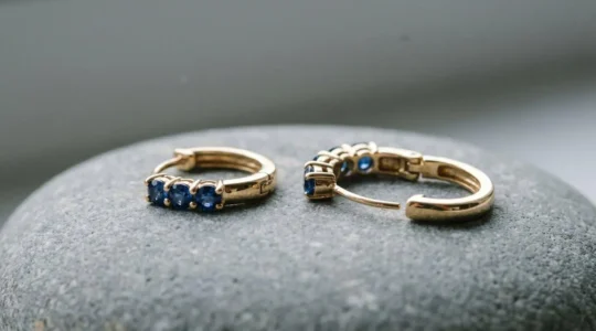 Gros plan sur une boucle d'oreille dormeuse en or avec saphir bleu, montrant le mécanisme de sécurité fermé