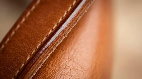 Gros plan sur la tranche d'un sac en cuir de qualité montrant une finition astiquée impeccable
