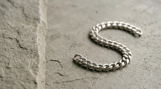 Gourmette masculine en argent massif posée sur une surface minérale, style épuré et raffiné
