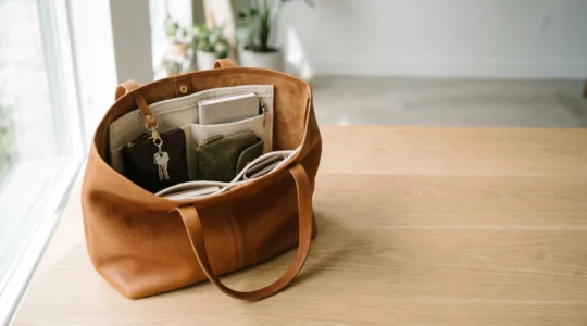 Grand sac cabas en cuir organisé avec compartiments et accessoires visibles sur fond minimaliste