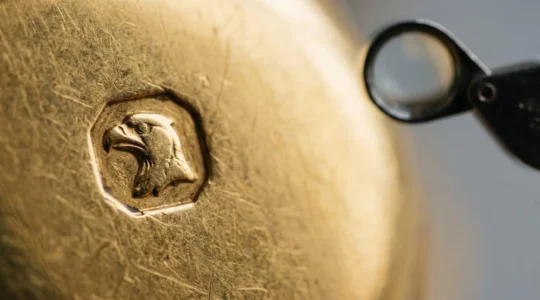 Examen minutieux d'un poinçon tête d'aigle sur un bijou en or français, symbole de garantie 750 millièmes